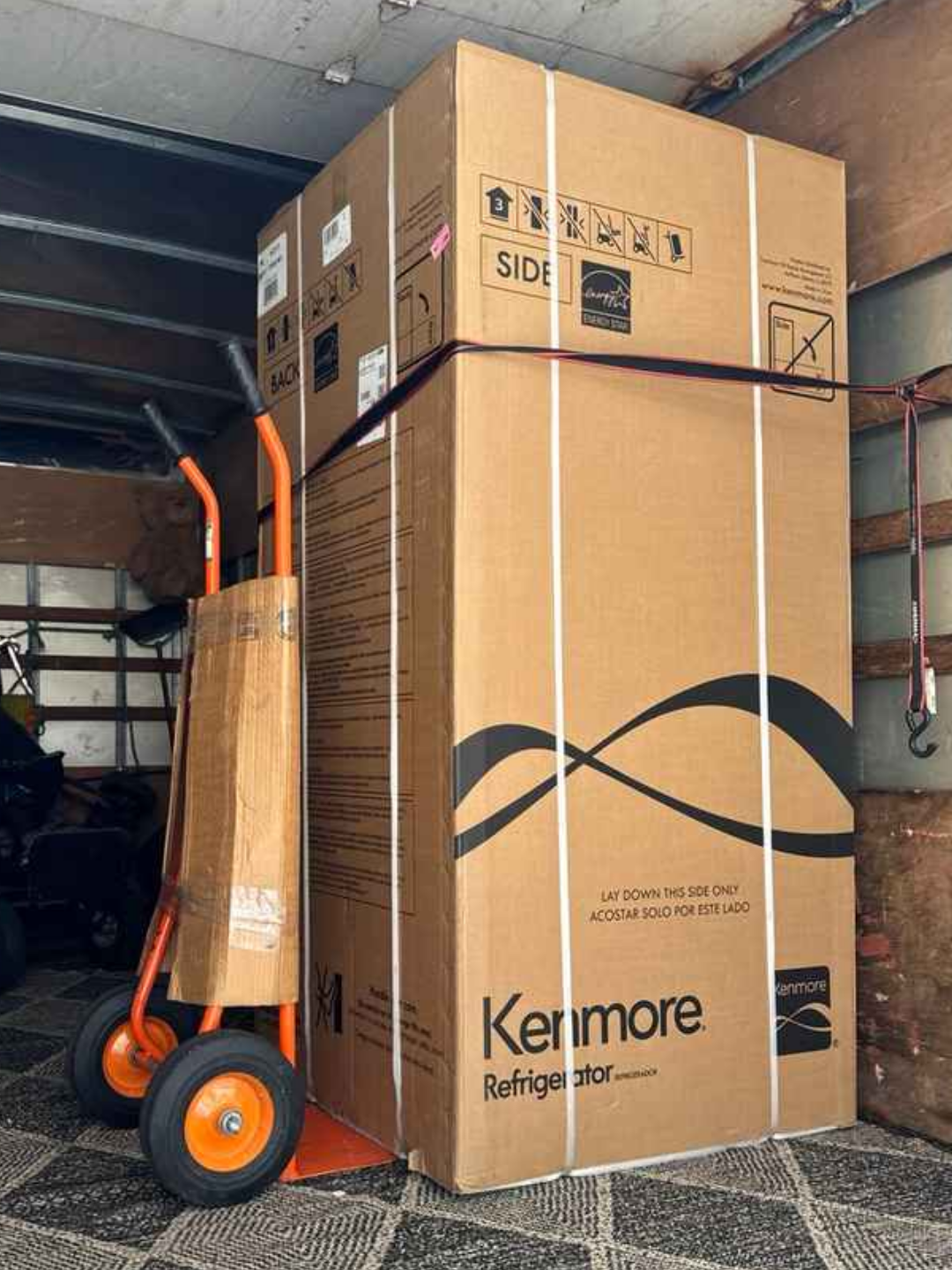 A refrigerator boxed and strapped against the box truck wall, secured by Luggers for safe transportation.