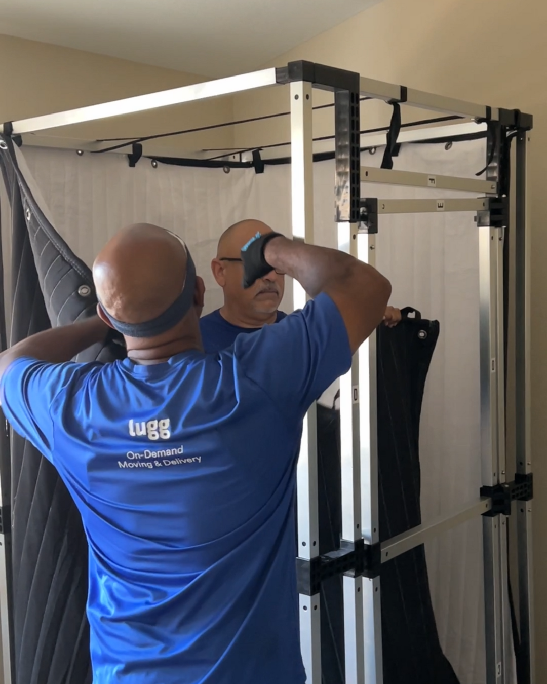 Two Lugg movers disassembling a large furniture piece to prepare it safely for transport.