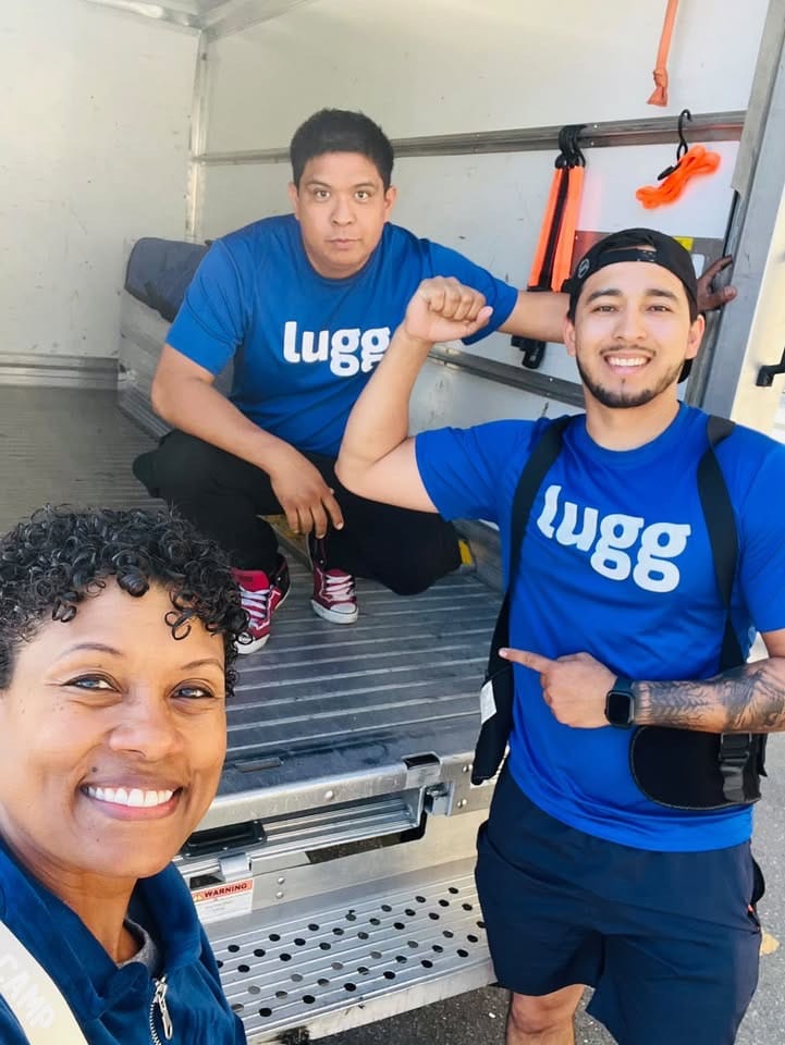 Two Lugg movers standing with a smiling customer inside a Lugg Box truck, showing the professional 2-person crew included with Lugg’s box truck moving service.