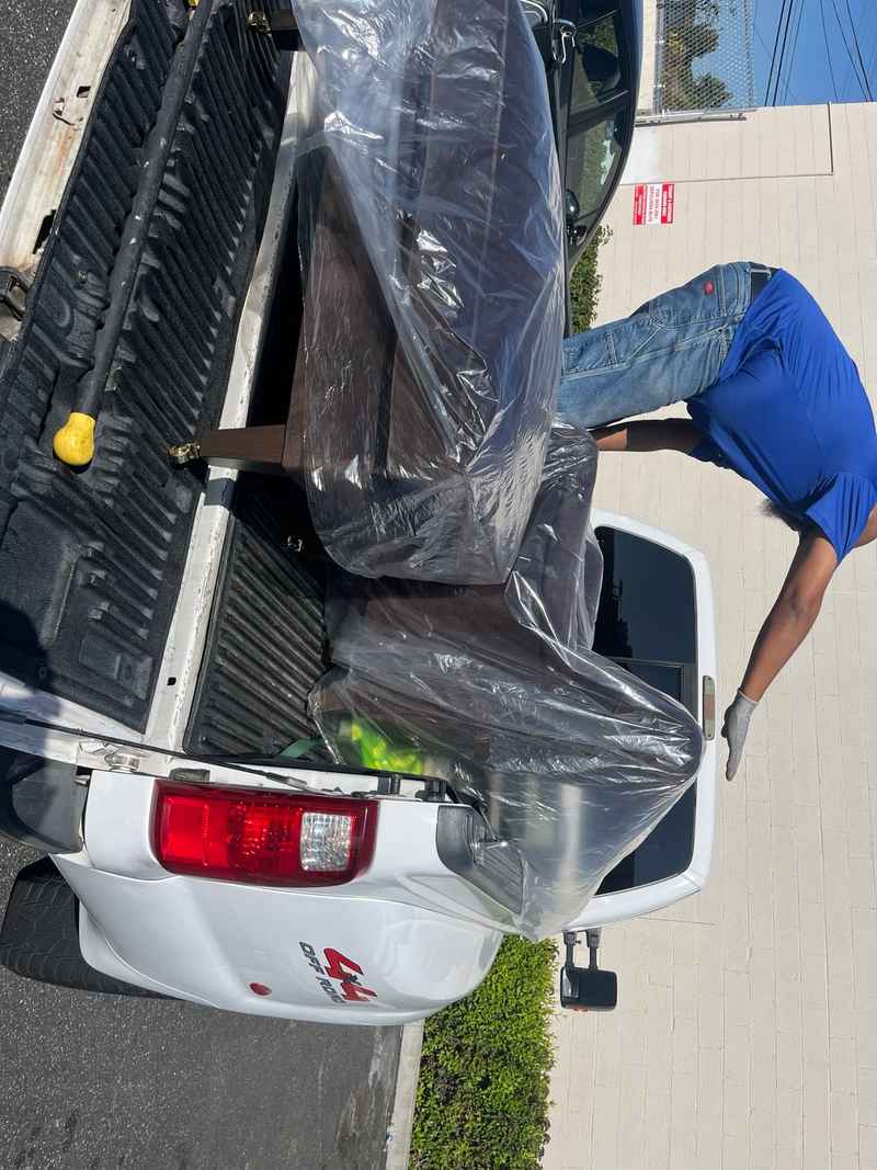 Lugg mover loading a wrapped sofa into a pickup truck after a furniture store purchase