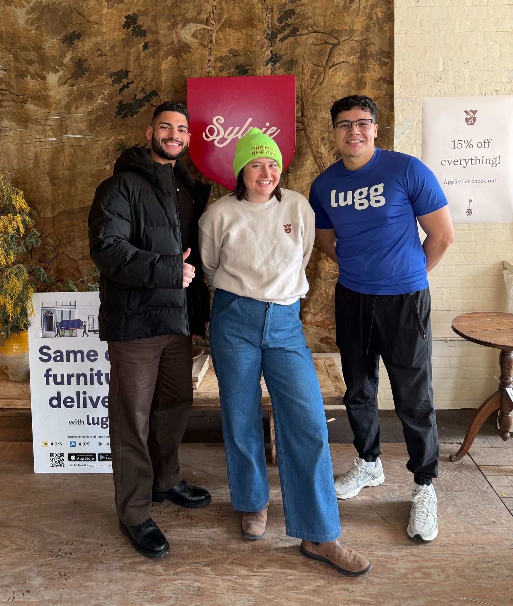 Lugg and Sylvie team members posing together at estate sale with Sylvie banner and Lugg delivery sign